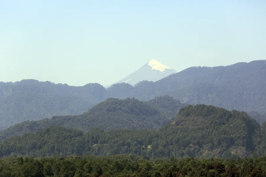 Volcán Lanín nevado visto desde la orilla sur del lago Calafquén, frontera Chile–Argentina, con el cono glaciarizado.